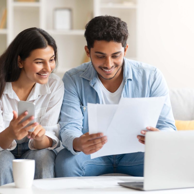 young-indian-couple-reviewing-document-with-lapto-2023-11-27-05-24-27-utc